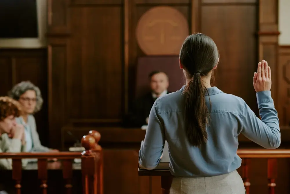 Femme prêtant serment la main levée devant un tribunal lors de son assermentation pour exercer ses fonctions d'agent.