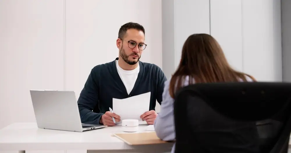 Recruteur tenant un dossier lors d'un entretien d'embauche avec une candidate pour la police municipale.