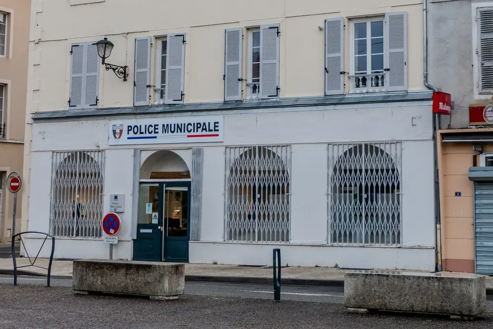 Façade d'un poste de police municipale avec enseigne officielle et fenêtres protégées par des grilles de sécurité.
