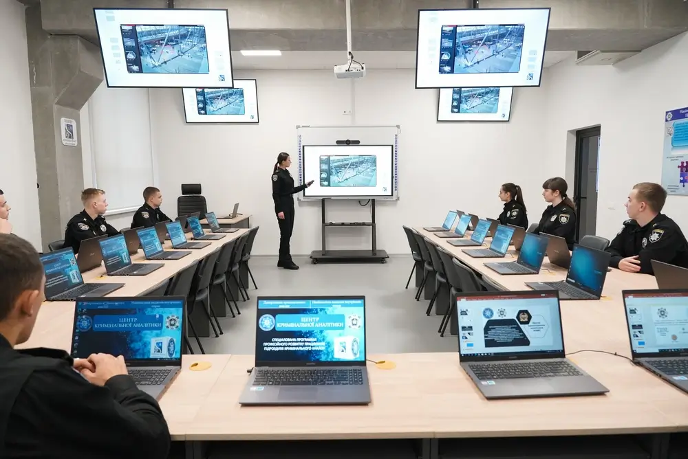 Élèves policiers en uniforme assistant à un cours théorique sur ordinateur dans une salle de formation numérique.